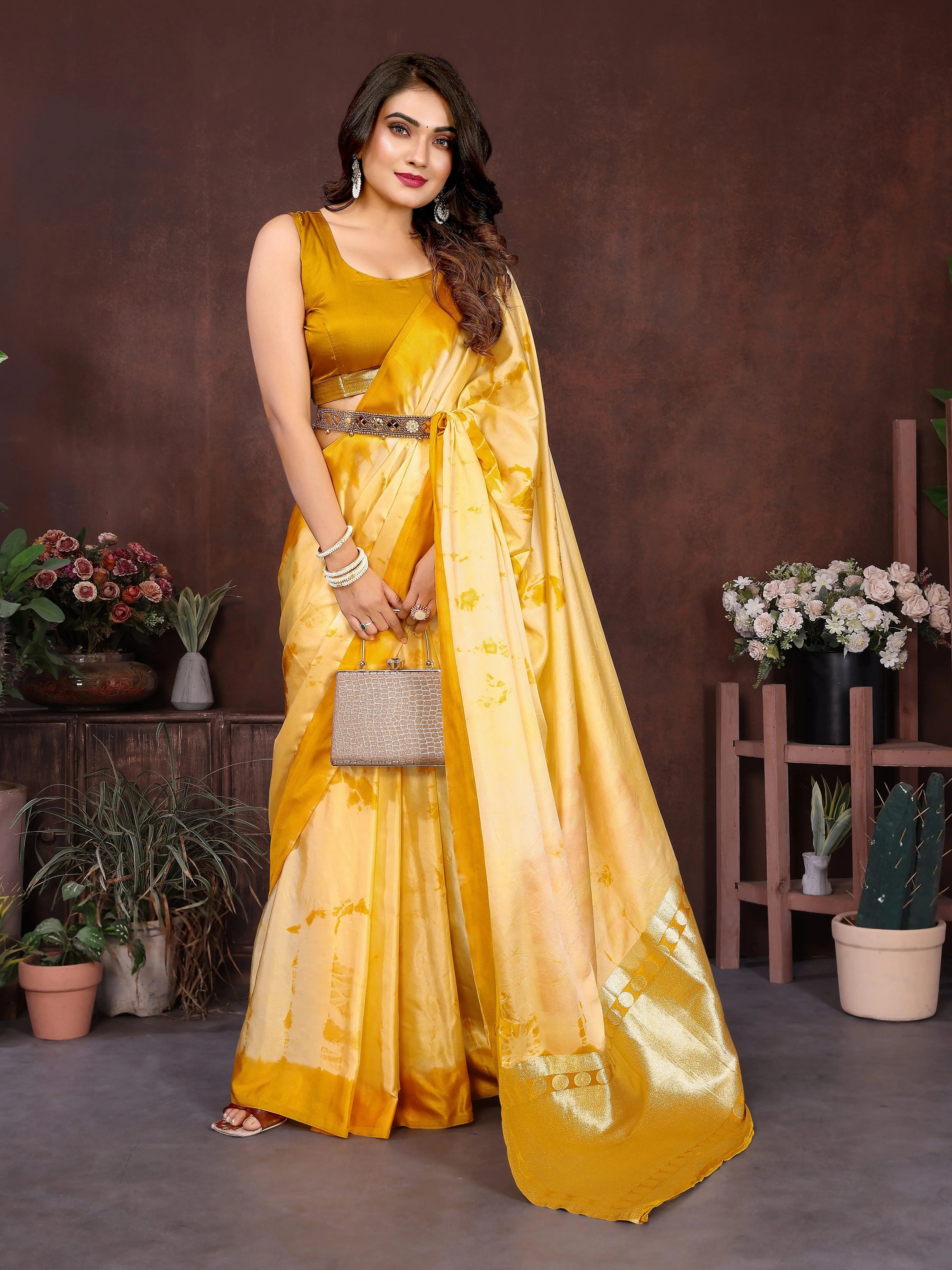 Woman wearing a traditional saree in a decorated room with flowers and white furniture.
